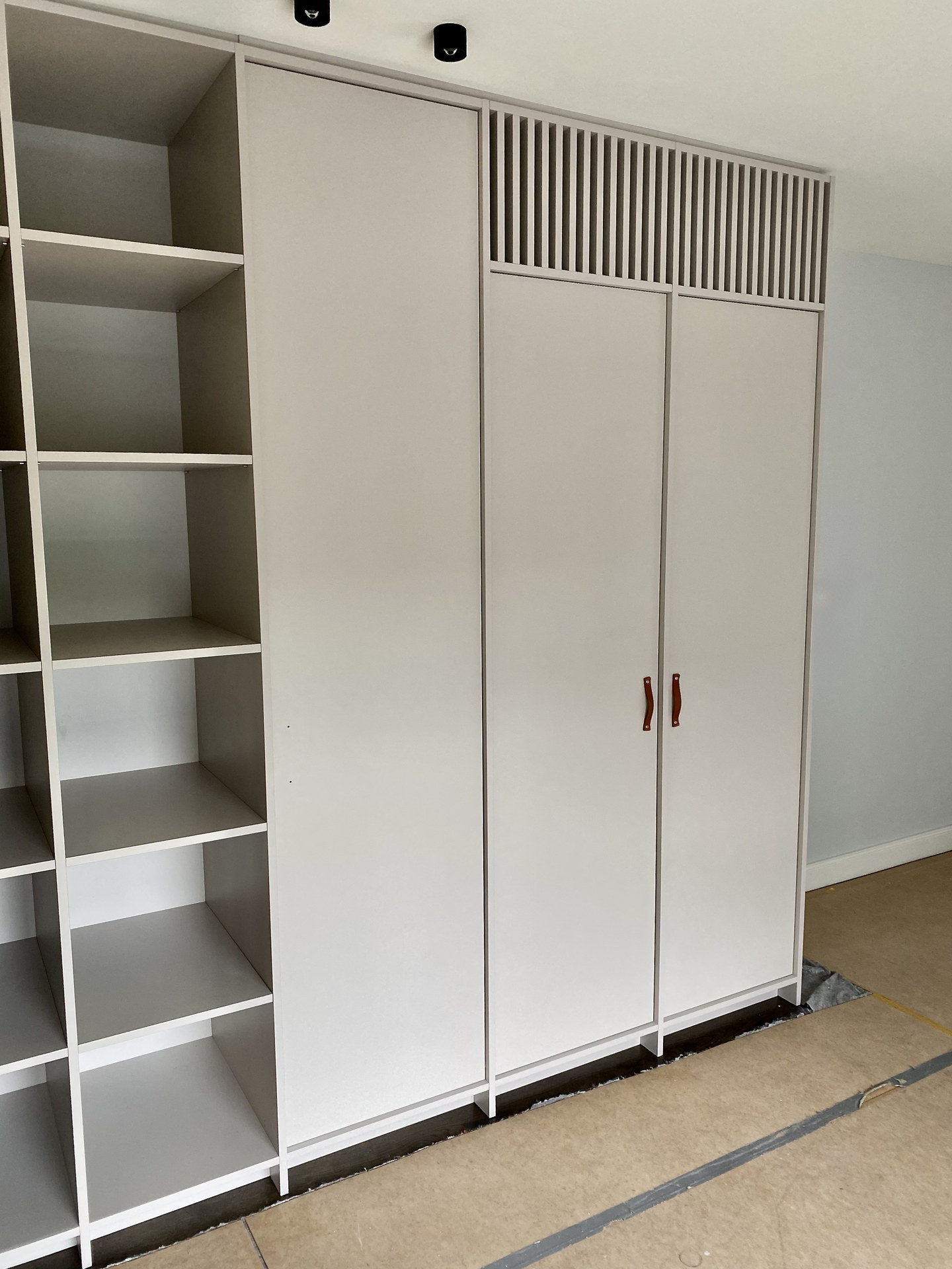 Maßgefertigter Einbauschrank in Weiß mit Lamellenaufsatz und Cognac-Ledergriffen
